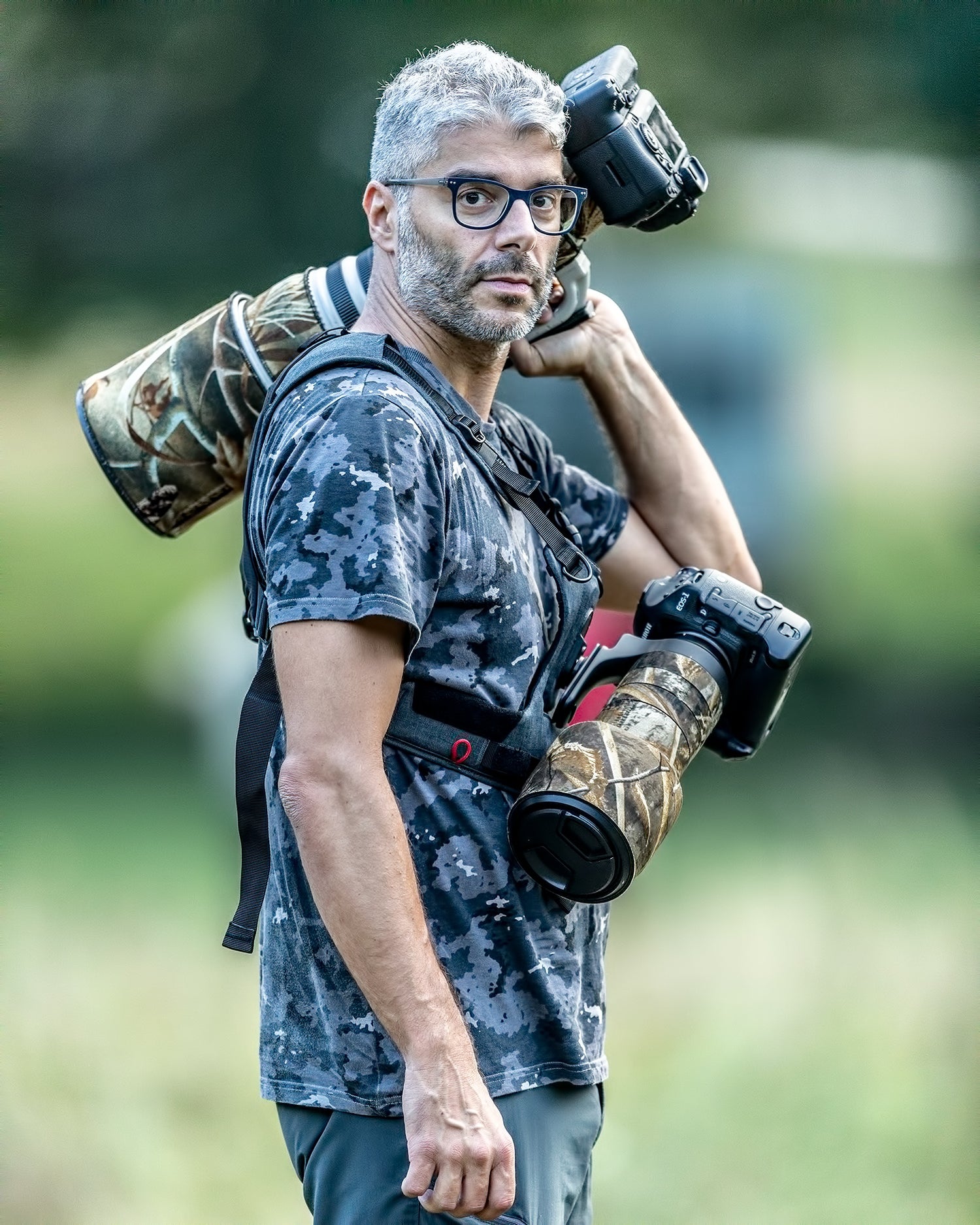 Photographer carrying large camera equipment with camera straps and camera slings