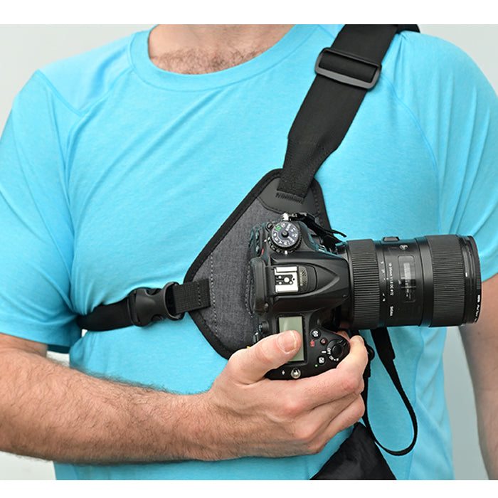 Man wearing camera sling harness while inserting a camera